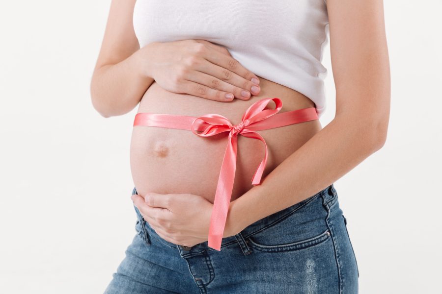 Cropped image of pregnant woman presetns a gift in the form of child over white background